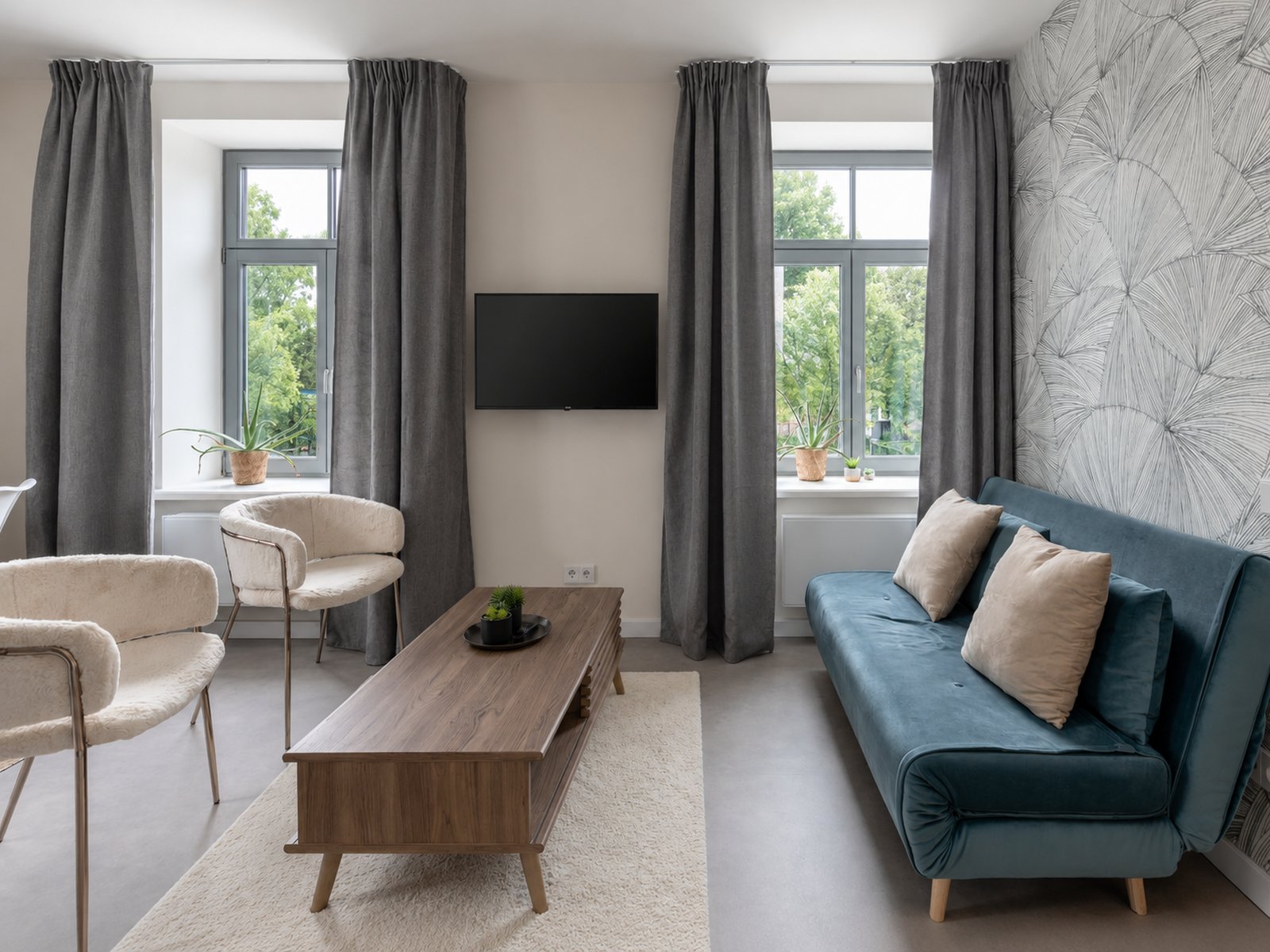 Living room with teal sofa, walnut coffee table, swivel-arm TV and hand-drawn wallpaper by the family's autistic son, 39m² pied-à-terre Kipsala Riga — Ruimte interior design