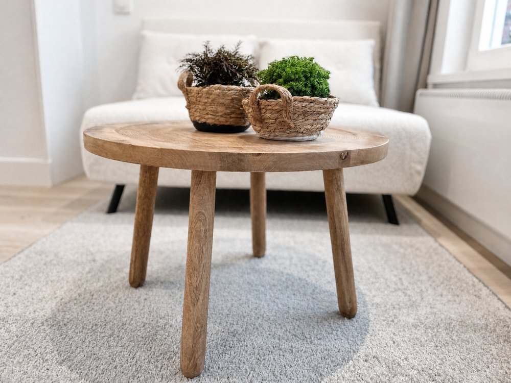 Detail of solid oak coffee table with woven baskets and plants in renovated studio apartment Oud-Zuid Amsterdam - Ruimte interior design