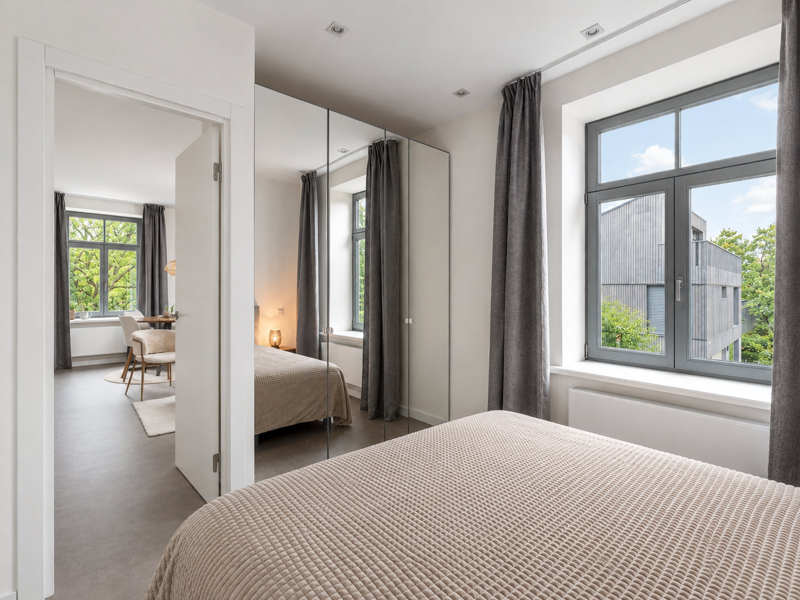 Compact bedroom with full-height mirrored wardrobe and open doorway to living room, renovated pied-à-terre Kipsala Riga — Ruimte interior design