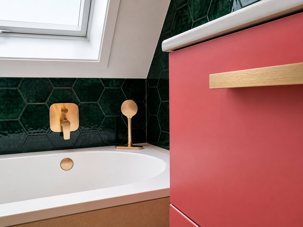 Bath detail in renovated Bussum bathroom showing deep green hex tiles, brushed brass wall-mounted tap and coral vanity unit
