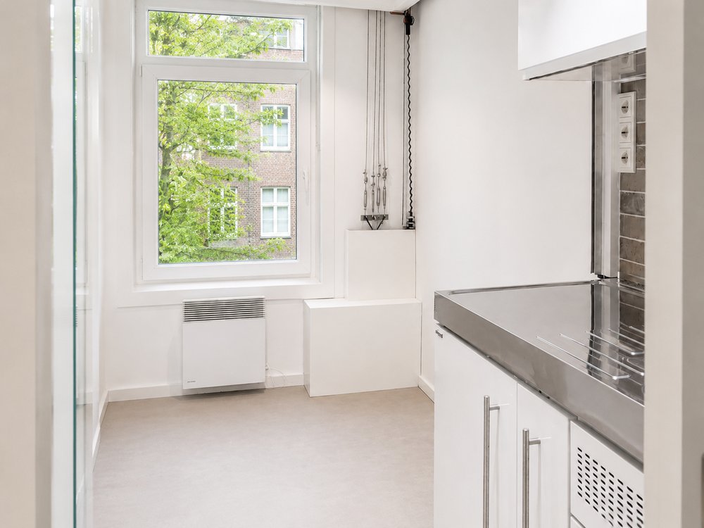 Empty floor with bed hoisted to ceiling, full width window and green tree view, micro apartment De Pijp Amsterdam - Ruimte interior design